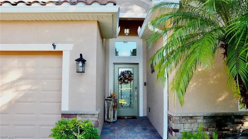 View of exterior entry featuring stone siding, stucco siding, an attached garage, and a tiled roof