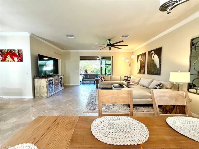 Living room featuring a ceiling fan, crown molding, and light tile patterned floors