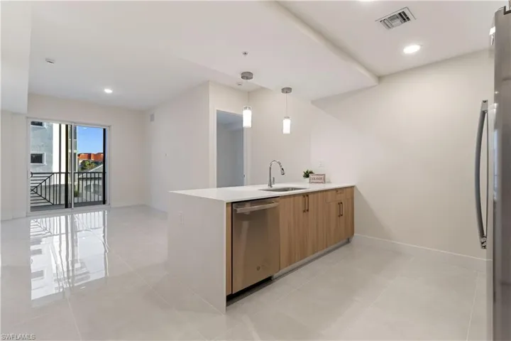 Contemporary kitchen featuring a white countertop island with an undermount sink and a stainless steel dishwasher