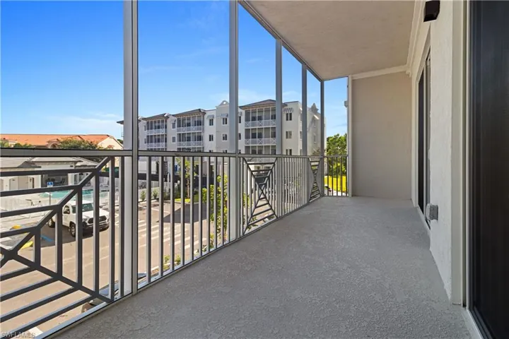 Screened private balcony featuring a textured concrete floor and decorative metal railings