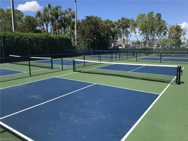 Multiple outdoor courts featuring blue and green playing surfaces, white court lines, and black netting