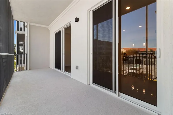 Spacious screened balcony with textured flooring, crown molding, and two sets of sliding glass doors