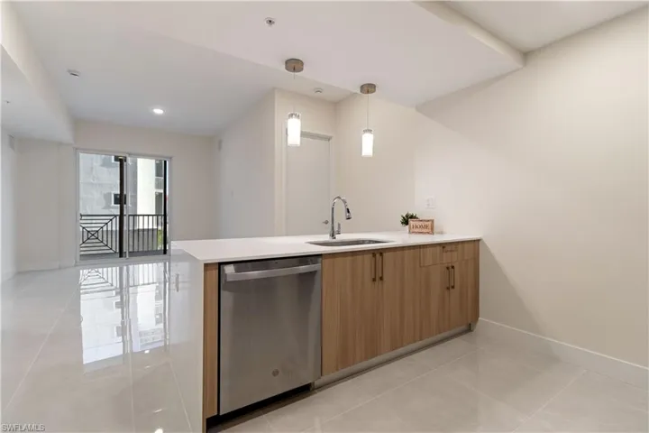 Modern kitchen island with a white countertop and wood-finish cabinetry, featuring an integrated stainless steel dishwasher and a stainless steel sink with a gooseneck faucet