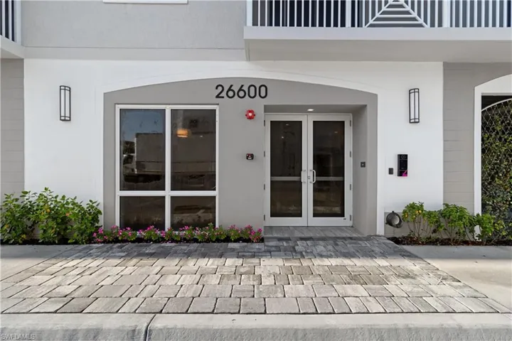 Modern building entrance featuring a double glass door, large storefront window, and decorative exterior lighting
