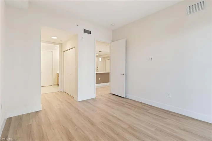 Spacious interior room featuring light wood-finish flooring and bright white walls