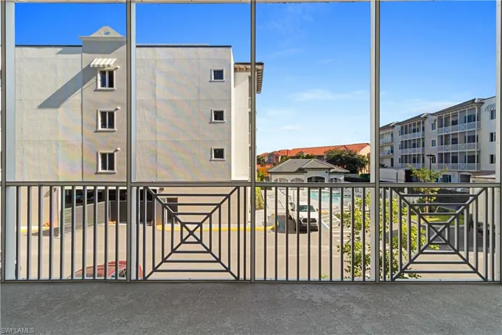 Screened balcony overlooking a pool area and surrounding buildings