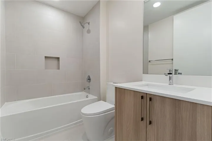Modern bathroom featuring a built-in tub with a tiled surround and recessed niche