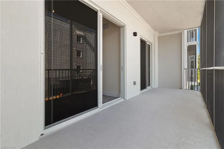 Screened balcony featuring a textured concrete floor and white stucco walls