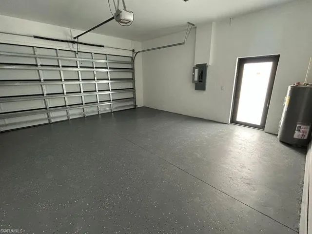 Garage featuring water heater, electric panel, and a garage door opener