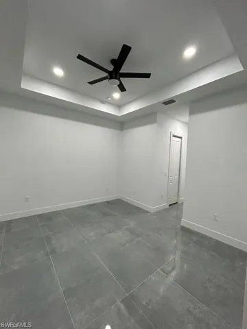 Spare room with a raised ceiling, recessed lighting, ceiling fan, and dark tile patterned floors
