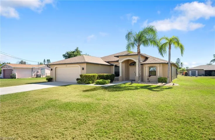 View of front facade with driveway, stucco siding, a front lawn, and a garage