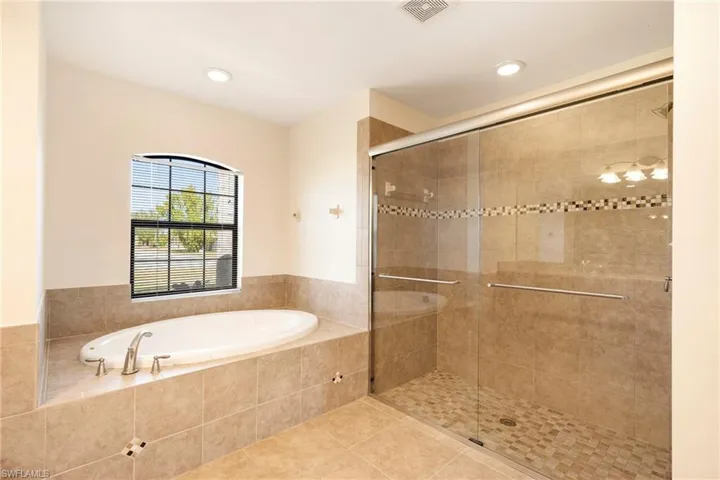 Bathroom featuring a bath, a stall shower, tile patterned flooring, and recessed lighting