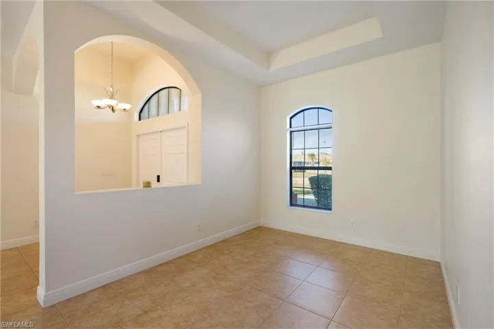 Spare room featuring hanging lights, light tile patterned floors, and a tray ceiling