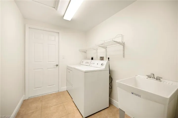 Laundry room featuring light tile patterned floors and washer and clothes dryer