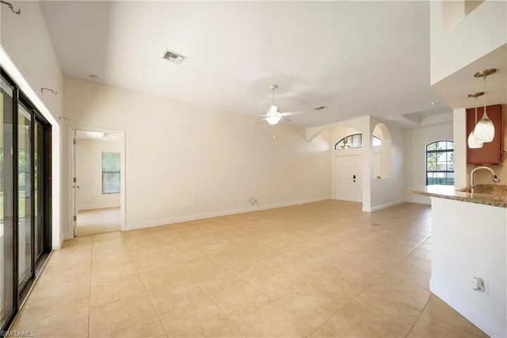 Unfurnished living room featuring light tile patterned floors, ceiling fan, and arched walkways