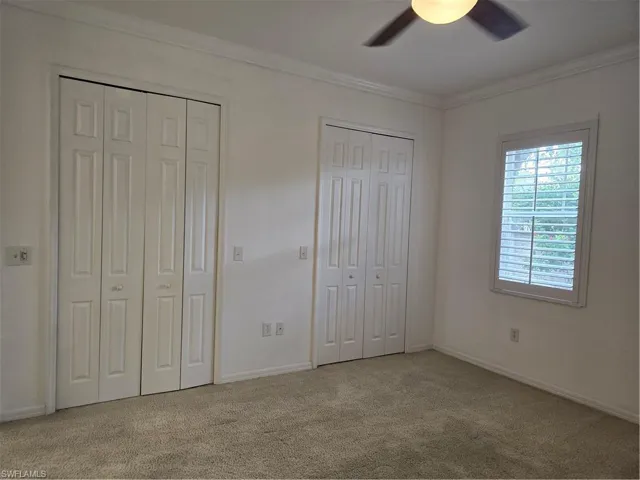 Ceiling fan with light fixture, plantation shutters, crown molding, wall-to-wall carpeting, and bi-fold closet doors