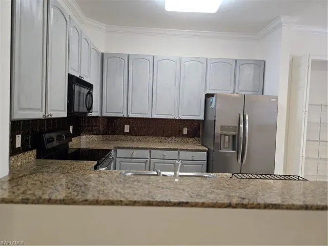Kitchen featuring granite countertops, stainless steel appliances, grey cabinetry, a tile backsplash, and crown molding