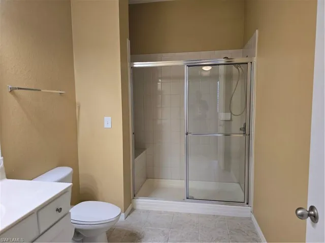 Shower enclosure with sliding glass doors, white tile surround, and an integrated bench
