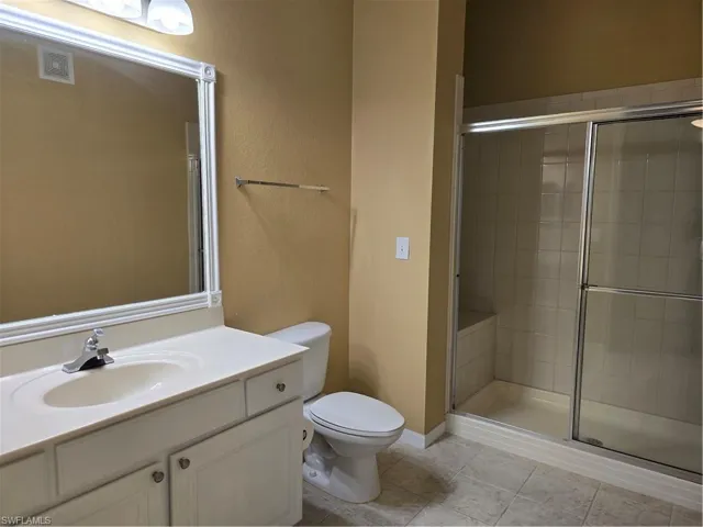 White vanity with integrated sink, framed mirror, and tile flooring