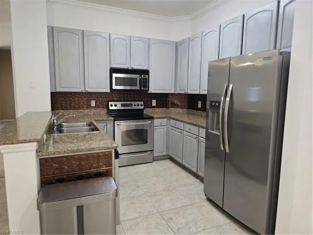 Kitchen featuring light-toned cabinetry, stainless steel appliances, a double basin sink, and tile flooring