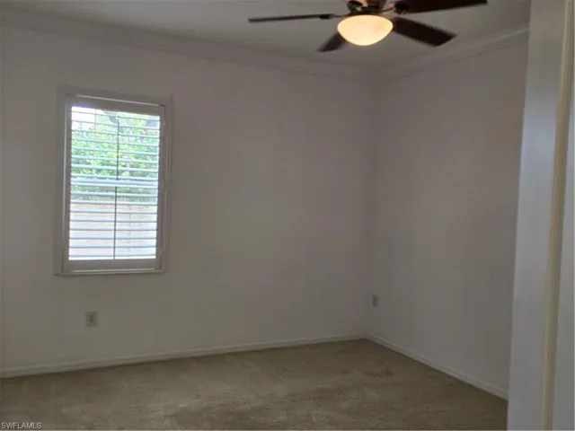 Window with plantation shutters, ceiling fan with integrated lighting, crown molding, and neutral-toned carpeting