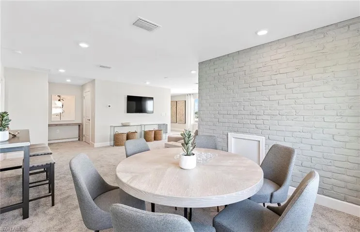 Dining room featuring brick wall and light colored carpet