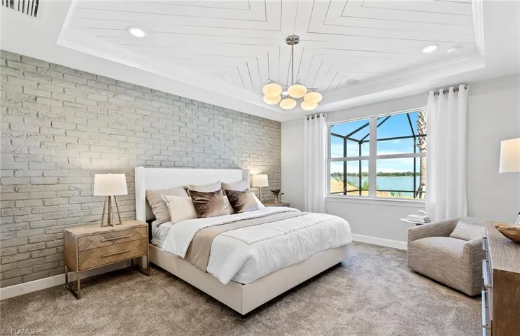 Bedroom featuring carpet, a water view, crown molding, brick wall, and a raised ceiling