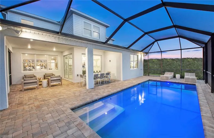 Pool at dusk featuring glass enclosure and a patio area