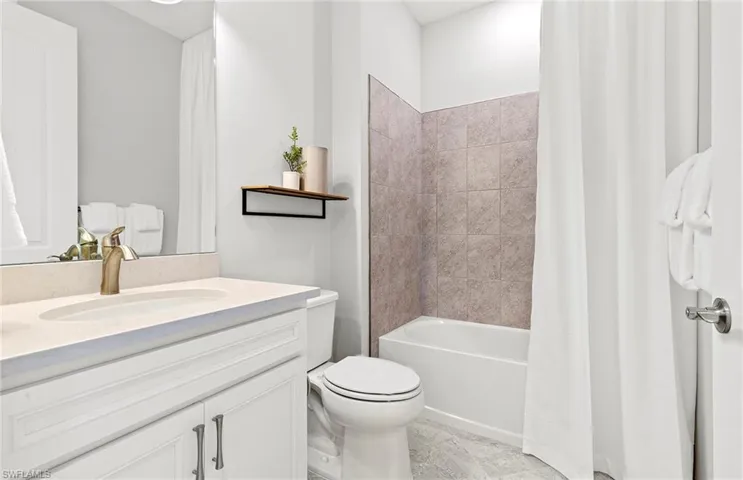 Full bathroom with shower / tub combo, vanity, tile patterned flooring, and toilet