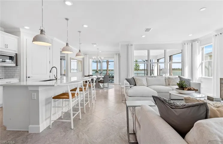 Tiled living room with sink, crown molding, a notable chandelier, and a wealth of natural light