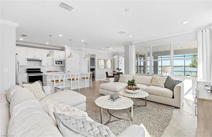 Tiled living room featuring sink, a water view, a chandelier, and ornamental molding