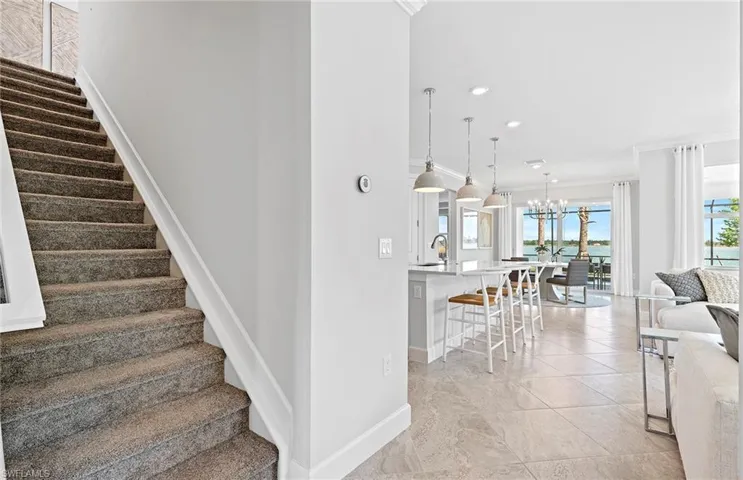 Staircase featuring light tile patterned flooring, sink, an inviting chandelier, and ornamental molding