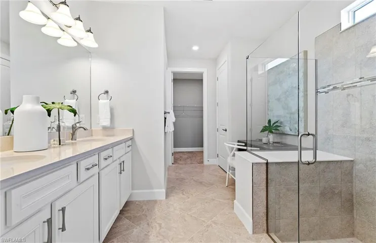Bathroom with tile patterned floors, double sink vanity, and an enclosed shower