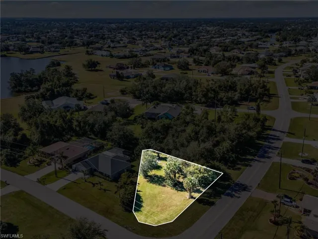 Aerial perspective of suburban area with property parcel outlined and a nearby body of water
