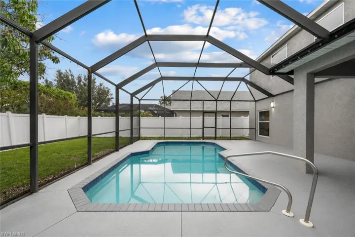 Screened-in pool area featuring a rectangular pool with integrated steps, a gray-painted concrete deck, and a privacy fence