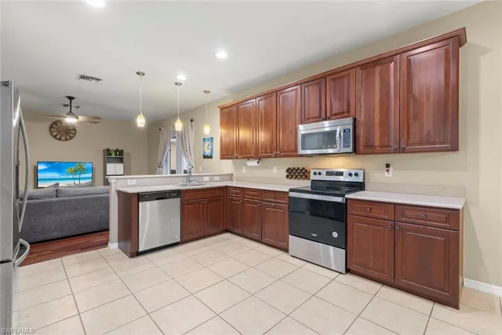 Kitchen with stainless steel appliances, open floor plan, hanging light fixtures, and a peninsula