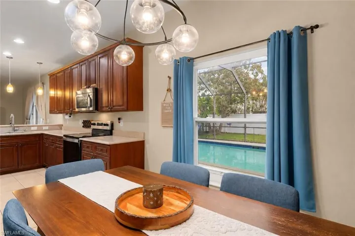 Dining area with a chandelier and window view of the pool