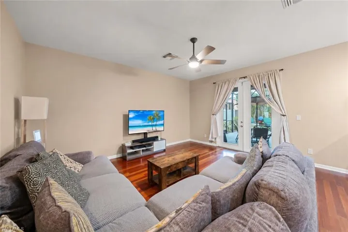 Spacious living area featuring wood-finish flooring, neutral wall tones, and direct outdoor access through double French doors