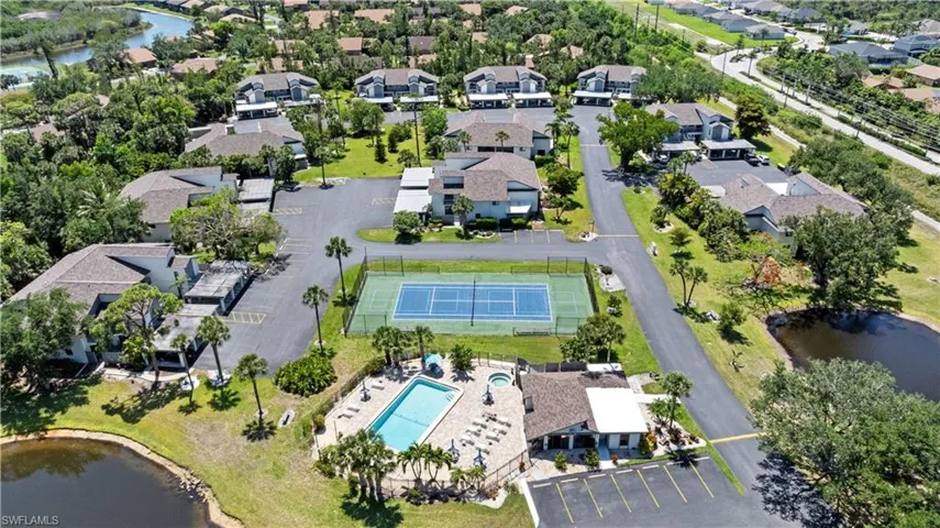 Aerial view of property and surrounding area featuring a pool, a nearby body of water, and nearby suburban area