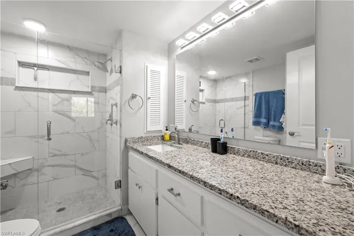 Full bathroom featuring vanity, toilet, and a marble finish shower