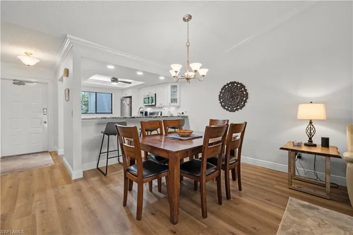 Dining room featuring crown molding, baseboards, a chandelier, wood finished floors, and recessed lighting