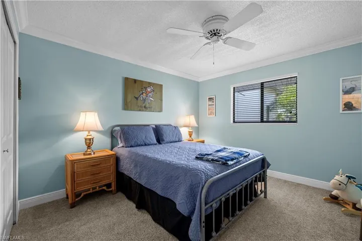 Carpeted bedroom featuring crown molding, a textured ceiling, baseboards, and ceiling fan