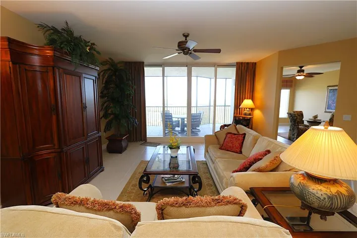 Living area with a wall of windows, ceiling fan, and light tile patterned floors