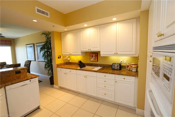 Kitchen featuring white cabinetry, white appliances, recessed lighting, light tile patterned floors, and dark stone counters