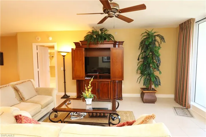 Living area with light tile patterned floors, ceiling fan, and healthy amount of natural light