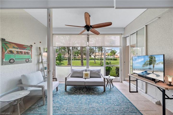 Large screened lanai overlooks green space with tennis courts and pool beyond.