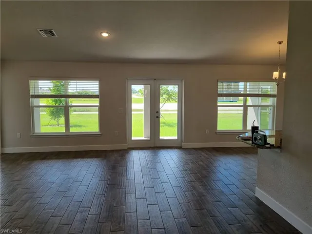 Unfurnished living room featuring an inviting chandelier and dark wood-type flooring