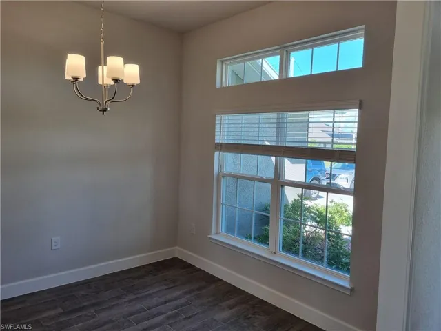 Spare room with an inviting chandelier and dark hardwood / wood-style flooring