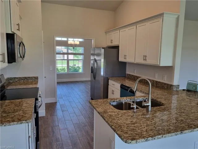 Kitchen featuring white cabinets, stainless steel appliances, dark wood-type flooring, and kitchen peninsula