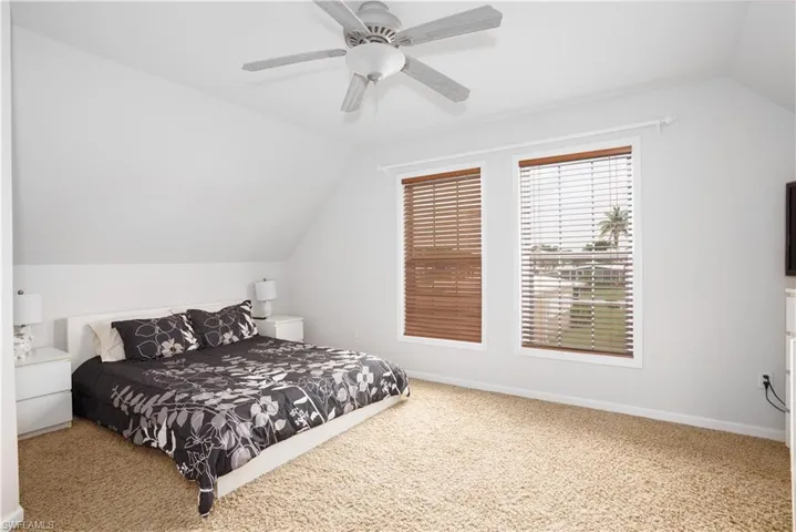 Carpeted bedroom featuring vaulted ceiling and ceiling fan
